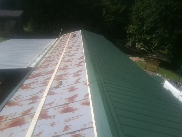 Old rusted panels beside newly installed green metal roofing — Wind Damage Roof Repair by Roofing Brothers in Chippewa Lake
