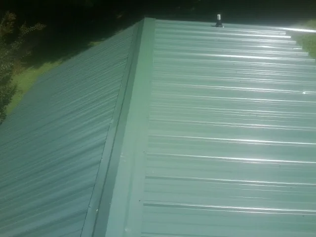 New green metal panels meeting at the ridge of a roof — Flat Roof Repair work by our crew in Chippewa Lake