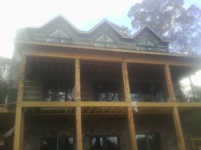Dormers and porch framing on a large log home under construction — Roof Coating work by our crew in Chippewa Lake