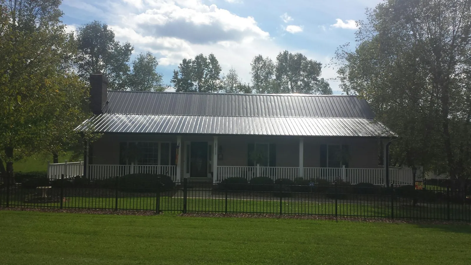Gray metal roof on a brick ranch with a full width front porch — Gutter Guard Installation work by our crew in Chippewa Lake