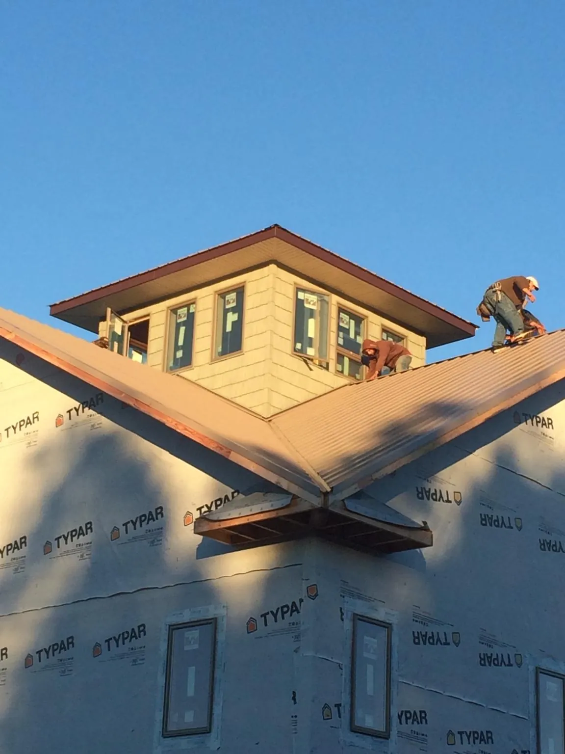 Roofers working around a rooftop cupola on a new metal roof at sunset — Roof Waterproofing in Chippewa Lake by Roofing Brothers